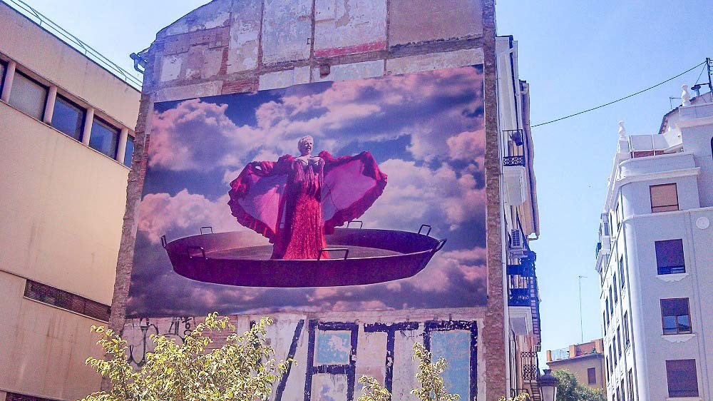 Photo of street art in El Carmen neighborhood. Shows a woman singing inside a paella pan.