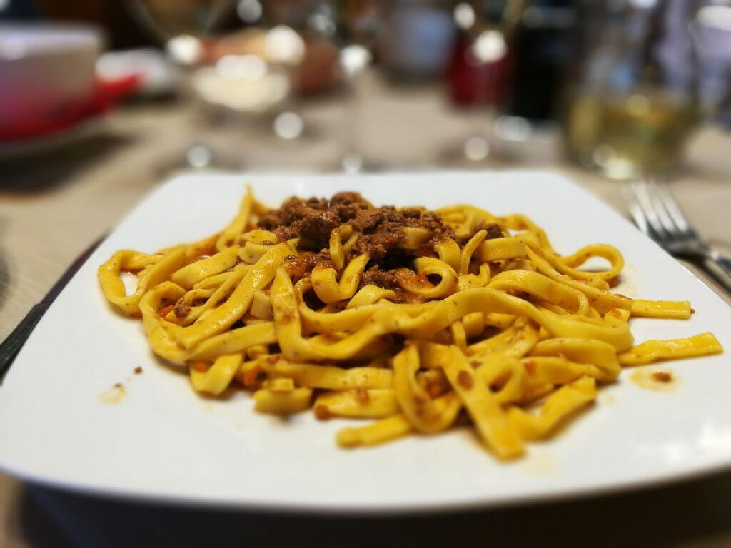 Photo of a plate of homemade pasta. It's tagliatelle served with ragu sauce.